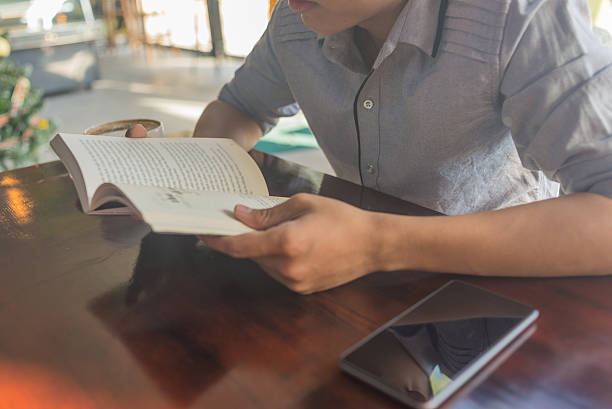 istock Human hand on the opened book with smartphone beside 513065936