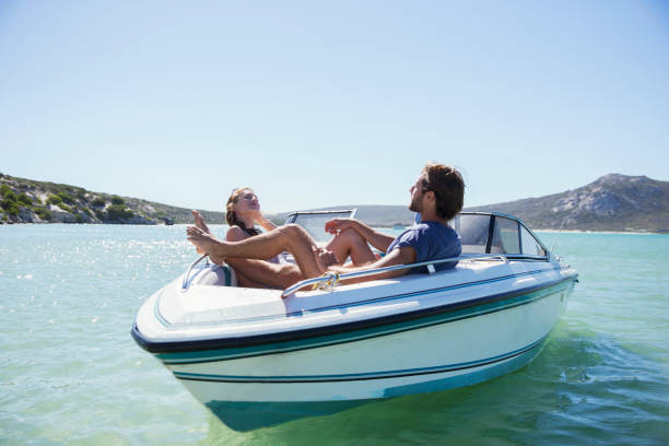 paar sitzt zusammen im boot auf dem wasser - motorbootfahren stock-fotos und bilder