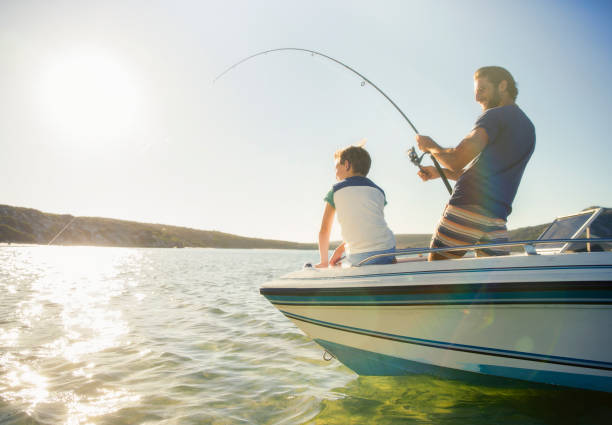 father and son fishing on boat - recreatieboot stockfoto's en -beelden