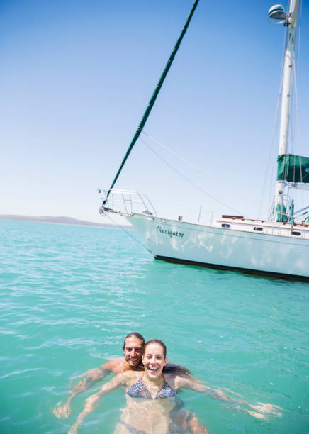 pareja nadando en el agua cerca del barco - clear sky water sports and fitness yacht fotografías e imágenes de stock