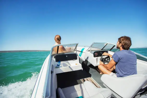 Photo of Man steering boat on water with girlfriend