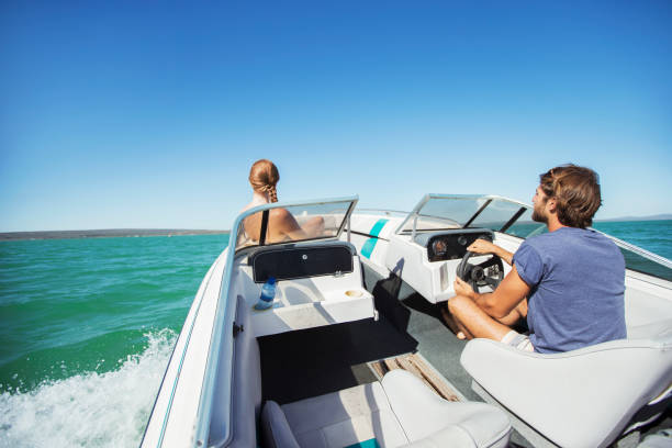 man steering boat on water with girlfriend - speedboat leisure activity relaxation recreational boat imagens e fotografias de stock