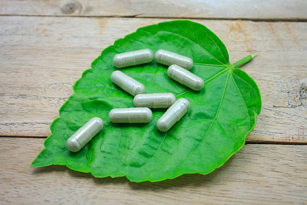 istock herbal medicine capsules with green herb leaf on wood table 513068570