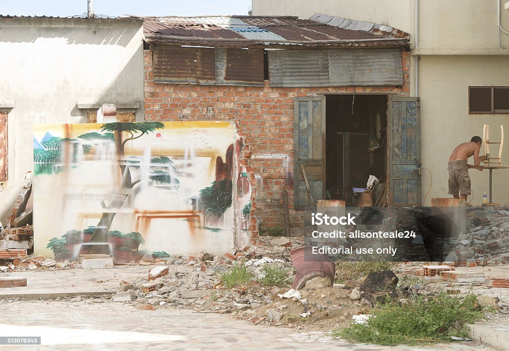 Artist works on a wooden stool, Danang, Vietnam Danang, Vietnam - July 24, 2010: An artist works on a wooden stool in an open yard, Danang, Vietnam Adult Stock Photo