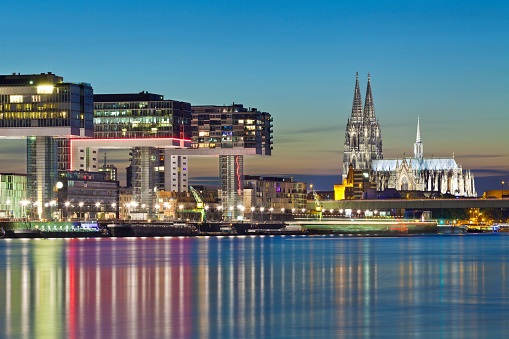 Illuminated Cologne Cathedral with the Rheinau Harbor (Rheinauhafen) buildings at night