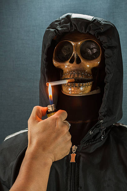istock Human skull smoking a cigarette on a black background 513104763