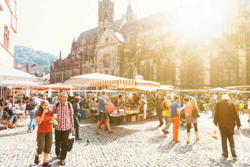 Freiburg, Germany - Sept 9, 2014: Central square in the City of Freiburg occupied by sellers of agricultural products, vines, famous German sausages on the sunny September day. This weekly event attracts many tourists. 