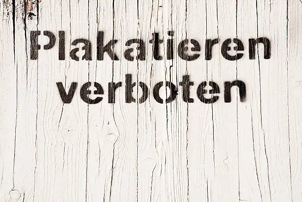 White wooden wall with text "Plakatieren verboten", meaning "pasting forbidden" in german