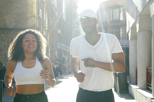 joyeux couple courir en extérieur à l'aube - marathon running london england competition photos et images de collection