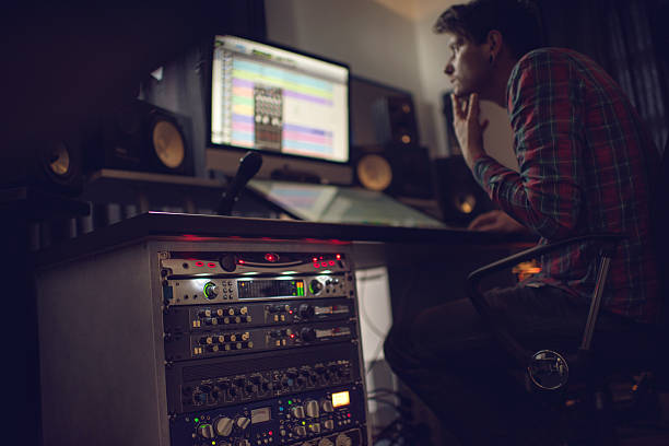 Audio rack in recording studio with producer in the background. Audio rack and sound recording equipment in recording studio with sound engineer working in the background. sound mixer photos stock pictures, royalty-free photos & images
