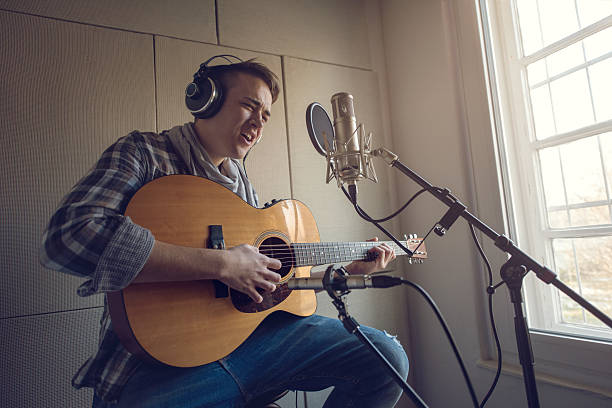 istock Young man playing acoustic guitar and singing in recording studio. 513110388