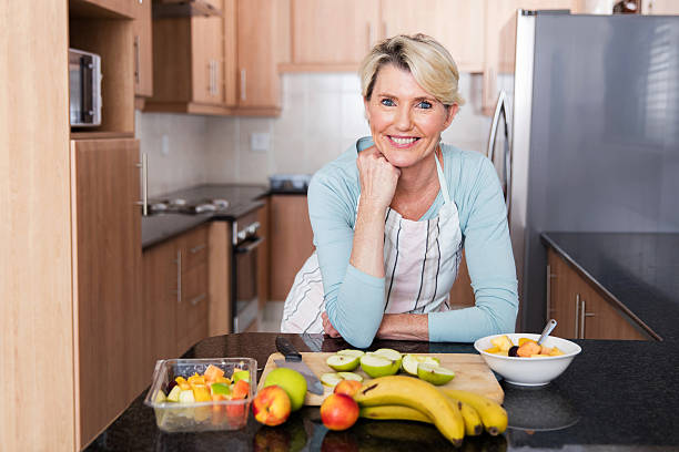 istock middle aged woman leaning against the kitchen counter 513110638