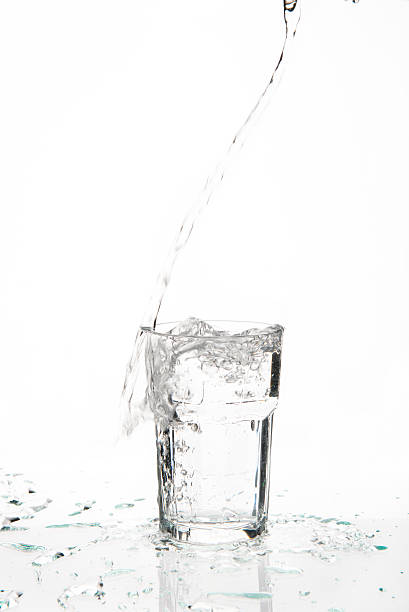 Overflowing glass of water on a glass table stock photo