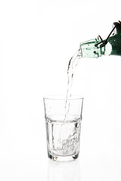istock Pouring water from glass bottle into glass 513113332