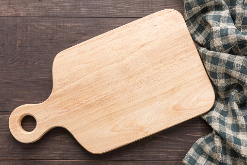 Cutting board with napkin on wooden background.