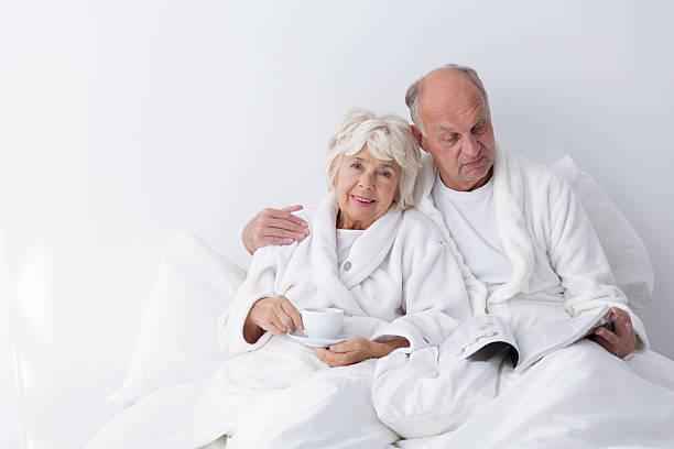 senior de yacer en la cama de matrimonio - hotel newspaper coffee reading fotografías e imágenes de stock