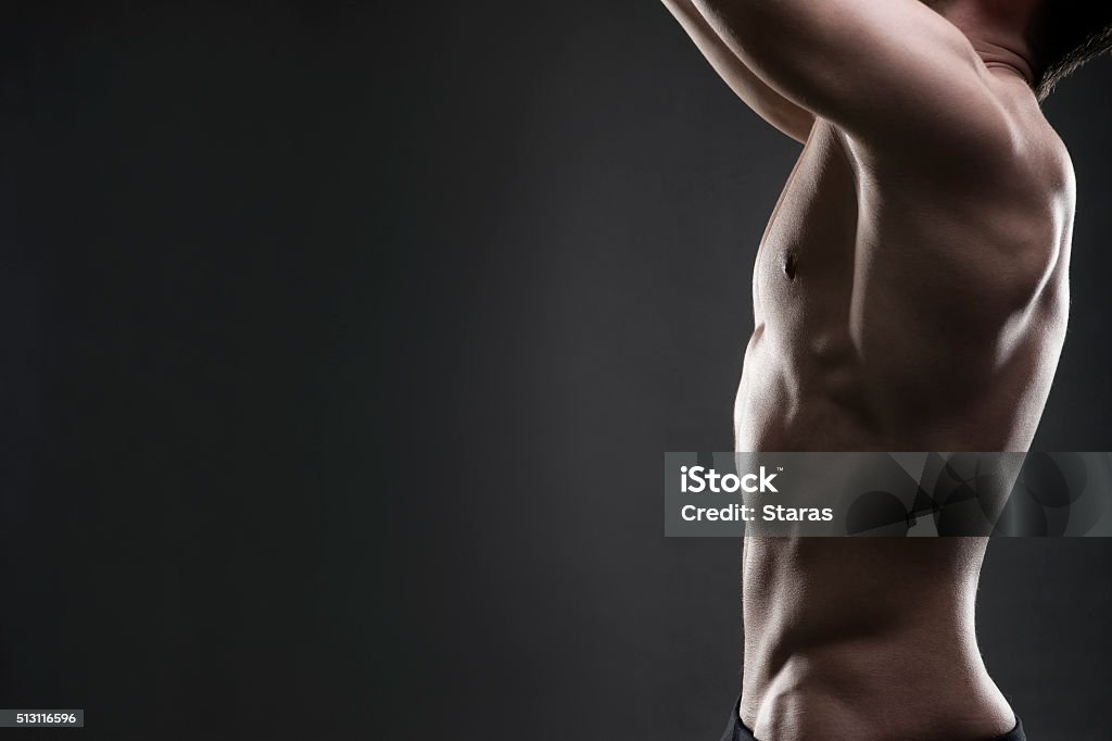 Handsome muscular bodybuilder posing on gray background Handsome muscular bodybuilder posing on gray background. Low key studio shot with copy space. Sexy male body Men Stock Photo