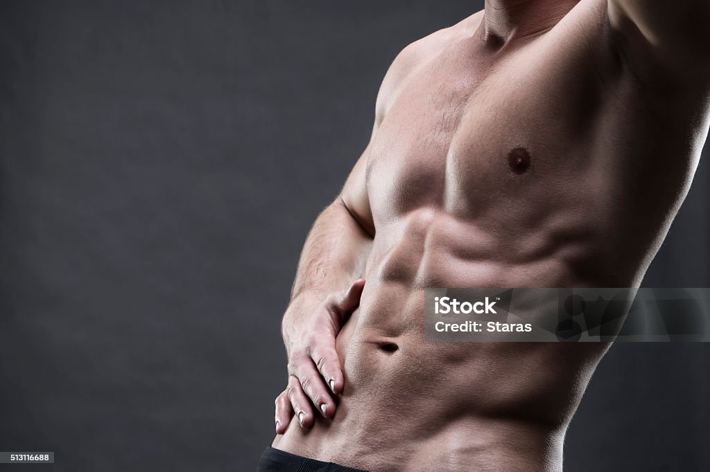 Handsome muscular bodybuilder posing on gray background Handsome muscular bodybuilder posing on gray background. Low key studio shot with copy space. Sexy male body Men Stock Photo