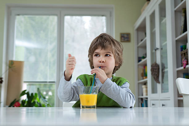 istock Little boy drinking orange juice 513118368