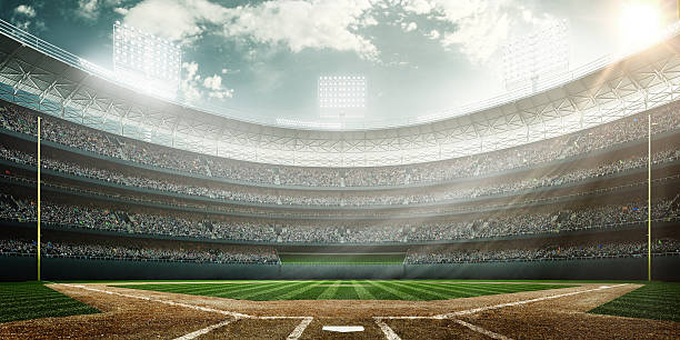 A wide angle of a outdoor baseball stadium full of spectators under a cloudy sky at midday. The image has depth of field with the focus on the foreground part of the pitch.