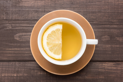 Ginger tea with lemon on the wooden background.