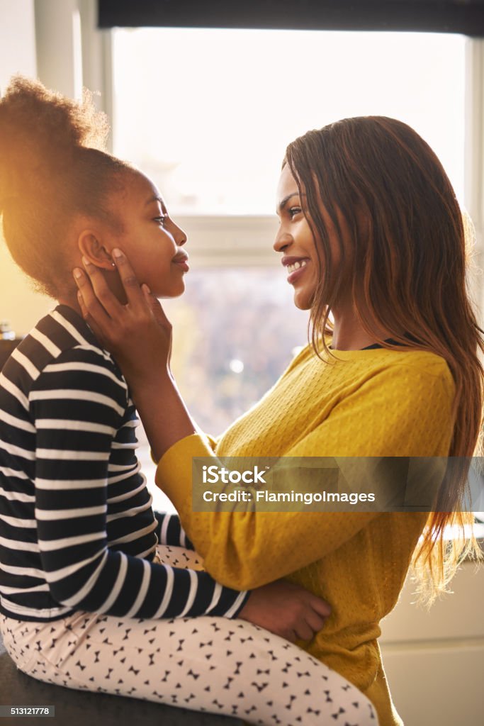 Black woman caressing her daughter Black woman caressing her daughter in a warm home, backlit sun Child Stock Photo