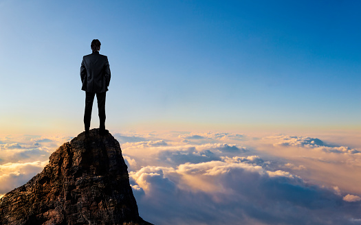  Young Businessman enjoys success on top of a cliff above the sea of clouds.