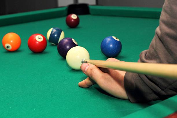 istock Billiard balls on green table and hand with cue 513124876