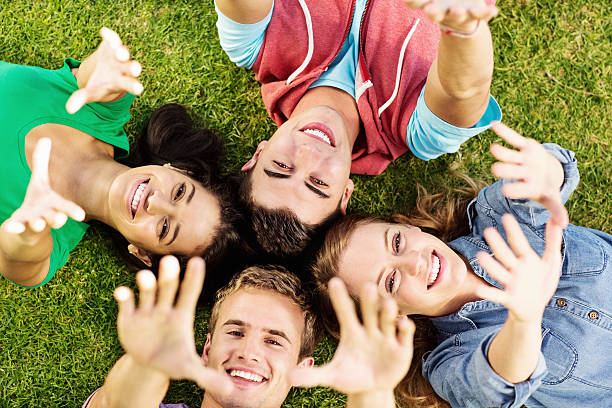 istock Friends With Arms Raised Lying On Grass In Park 513127246