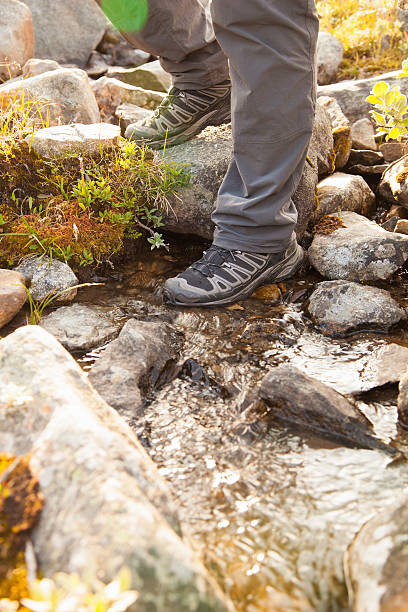 istock hiker crossing a river. legs in boots 513127910