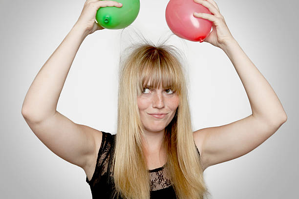 young beautiful blond haired girl with electric loaded balloons young beautiful blond haired girl with electric loaded balloons in front of grey background girl flex stock pictures, royalty-free photos & images