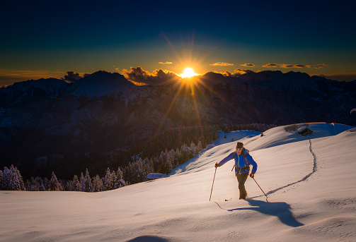 Ascending to the top. Ski mountaineering Cross country skiing alone uphill into silence at sunset