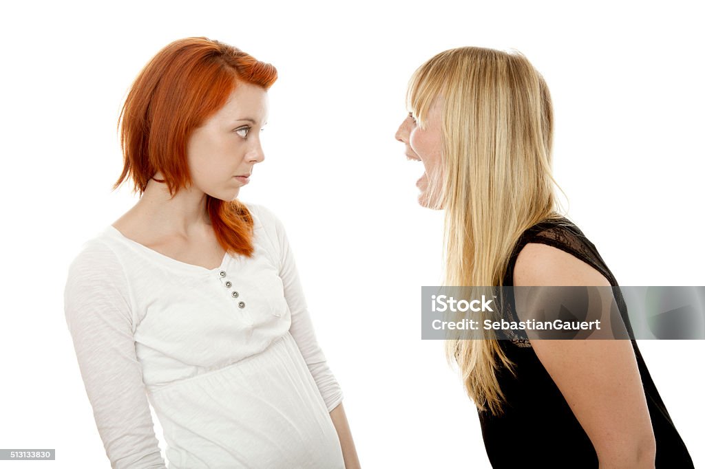 young beautiful red and blond haired girls is sorry fighting young beautiful red and blond haired girls in front of white background Adolescence Stock Photo