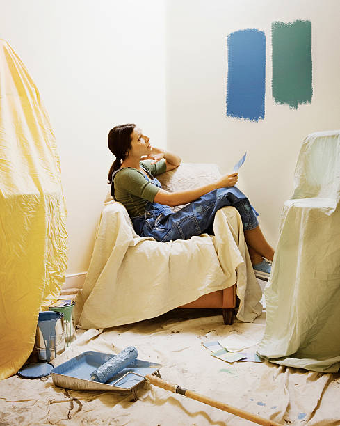 Woman holding up paint colors in room to be painted.