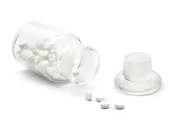 Generic glass bottle isolated with pills spilling out