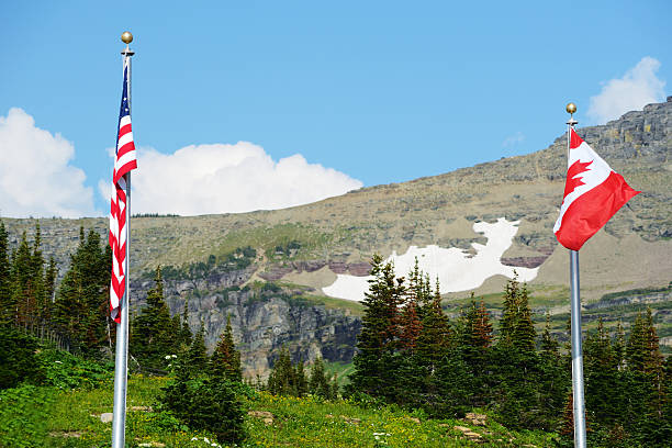 istock USA and Canada Flags flying at Logan's Pass. 513160065