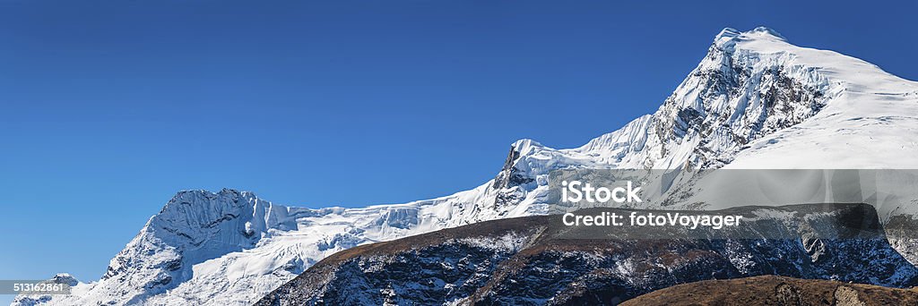 White winter mountain peak tumbling glaciers high in Himalayas Nepal Clear blue high altitude skies over snow capped summit, dramatic ridges, glaciers and icefalls deep in the Himalayan mountain wilderness of the Sagarmatha National Park, Nepal. ProPhoto RGB profile for maximum color fidelity and gamut. Adventure Stock Photo