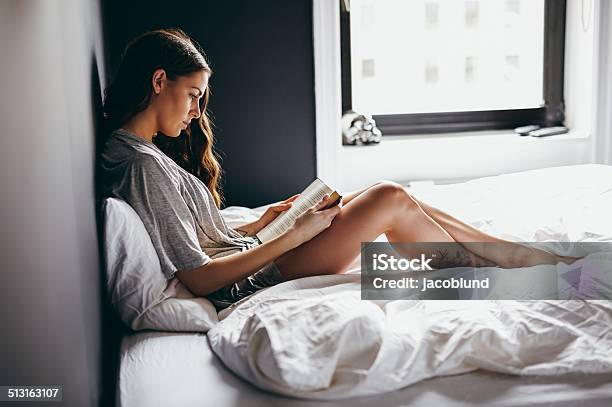 Young Woman Reading Book On Bed At Home Stock Photo - Download Image Now - Bed - Furniture, Reading, One Woman Only