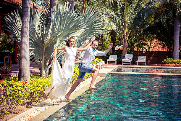 bride and groom jumping in the pool