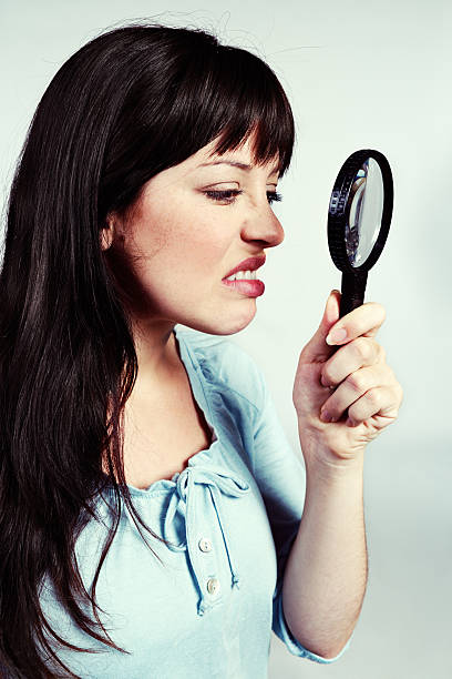 istock Eeuw! Cute young brunette looks through magnifying glass, grimacing 513182861