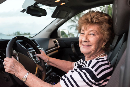 Smiling senior caucasian woman driving her vehicle