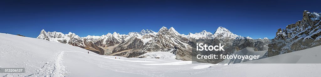 Mountaineers climbing high altitude peaks below Everest Himalayas Nepal The iconic pyramid peak of Mt. Everest (8848m) overlooking mountaineers and Sherpas climbing the snowy glacier to Mera Peak high camp above the remote and dramatic summits of the Himalayas, Nepal. ProPhoto RGB profile for maximum color fidelity and gamut. Adventure Stock Photo