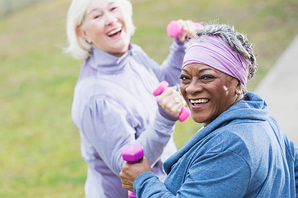 Senior women exercising Senior women (60s) exercising in park.  Focus on African American woman. 60 69 years stock pictures, royalty-free photos & images