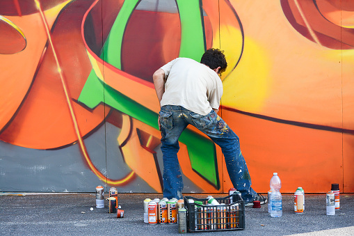 Hand of graffiti artist spraying a wall