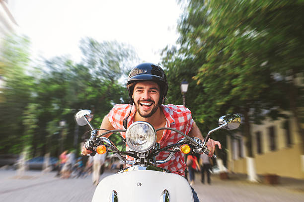 Smiling Young Man Riding Motor Scooter Smiling Young Man Riding Motor Scooter in the city. Speed motion blur concept. moped stock pictures, royalty-free photos & images