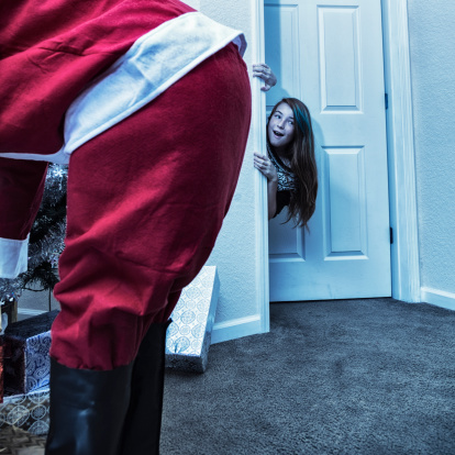A young teenager girl is surprised but happy to see Santa Claus as she peeks around the doorway late at night on Christmas Eve. Is Santa real after all, or is that just my silly Dad?? :) Toned image. (2014 Orlando City Beautiful 4 Lypse)