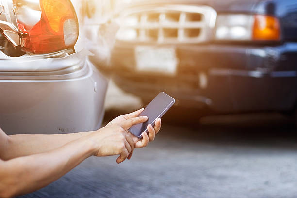 hombre usando teléfono inteligente en la carretera después del accidente de tráfico - accidente de automóvil fotos fotografías e imágenes de stock
