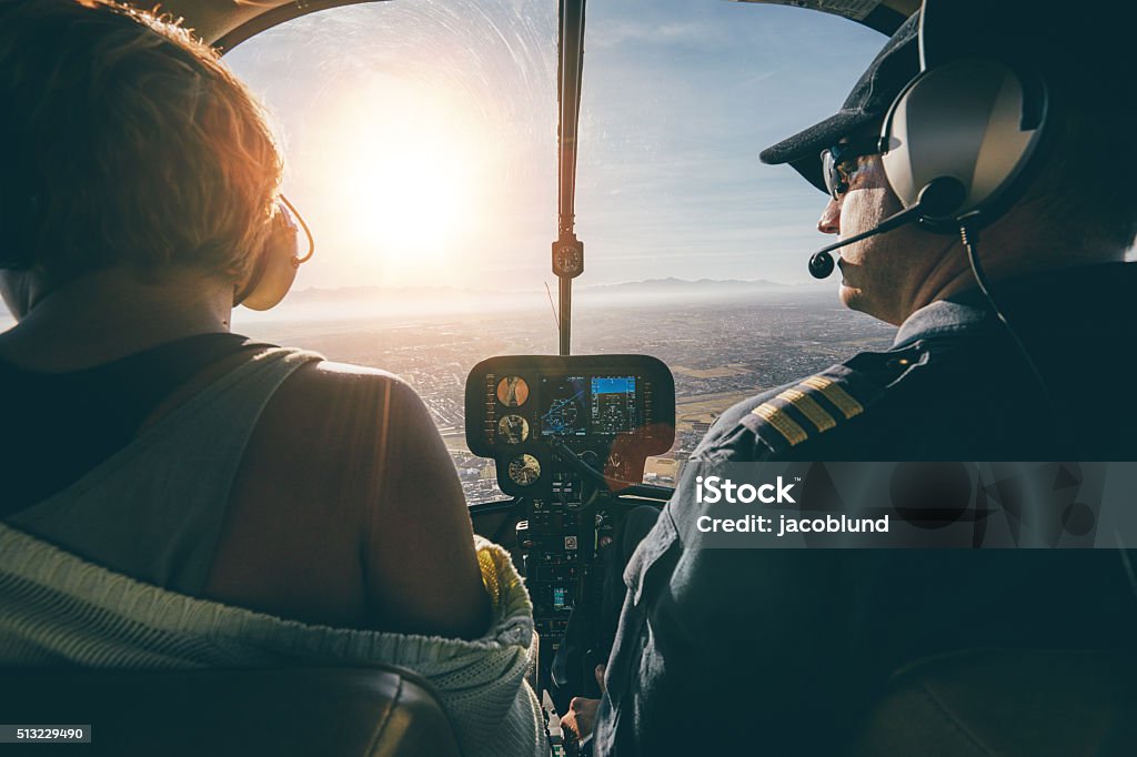 Man flying a helicopter with his copilot Rear view of male and female pilots flying a helicopter on sunny day. Man flying a helicopter with his copilot looking outside the aircraft. Helicopter Stock Photo
