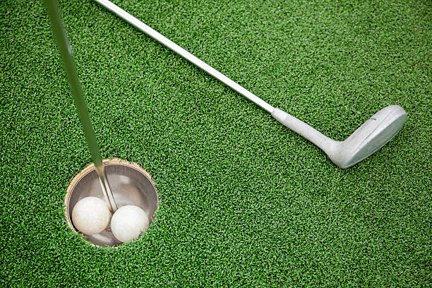 istock Golf club on green grass with golf ball in hole 513229584