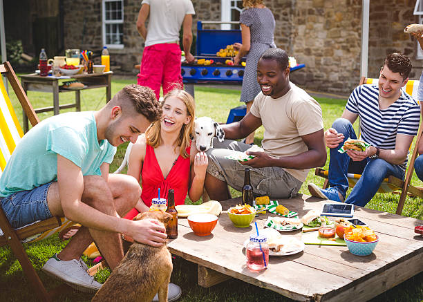 Group of Friends at a BBQ Group of friends having fun at a BBQ garden party. backyard party stock pictures, royalty-free photos & images